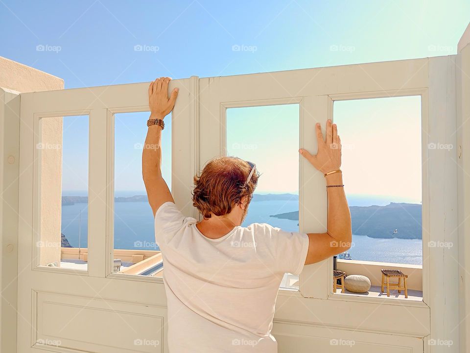 man looking Sea, out of Window in santorini
