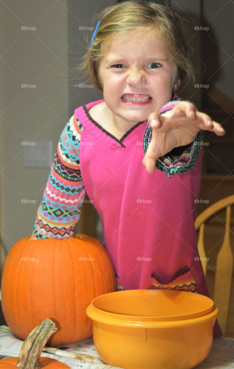 girl cleaning out pumpkin with scary face