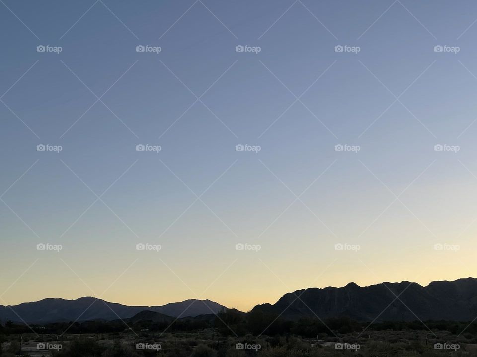 A yellow sunset with jagged mountains.