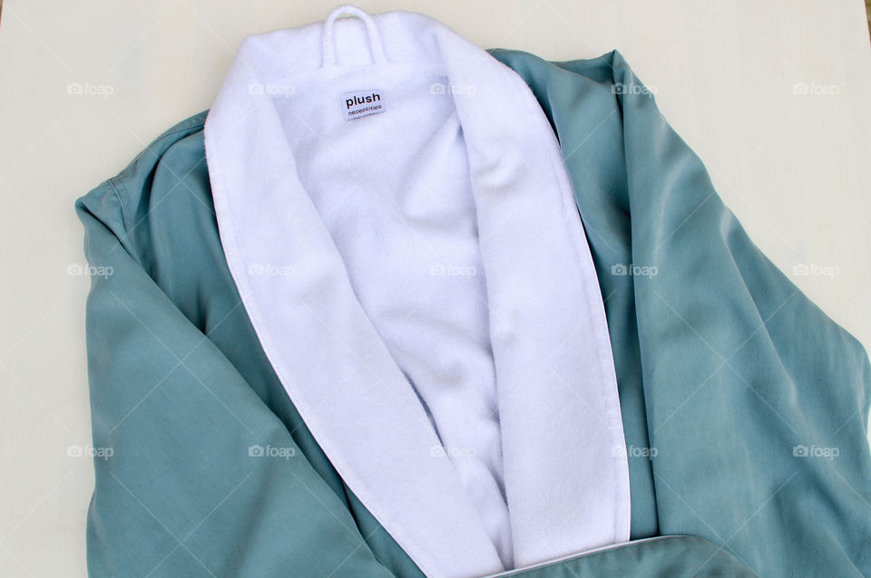Blue bathrobe laid out on a white surface
