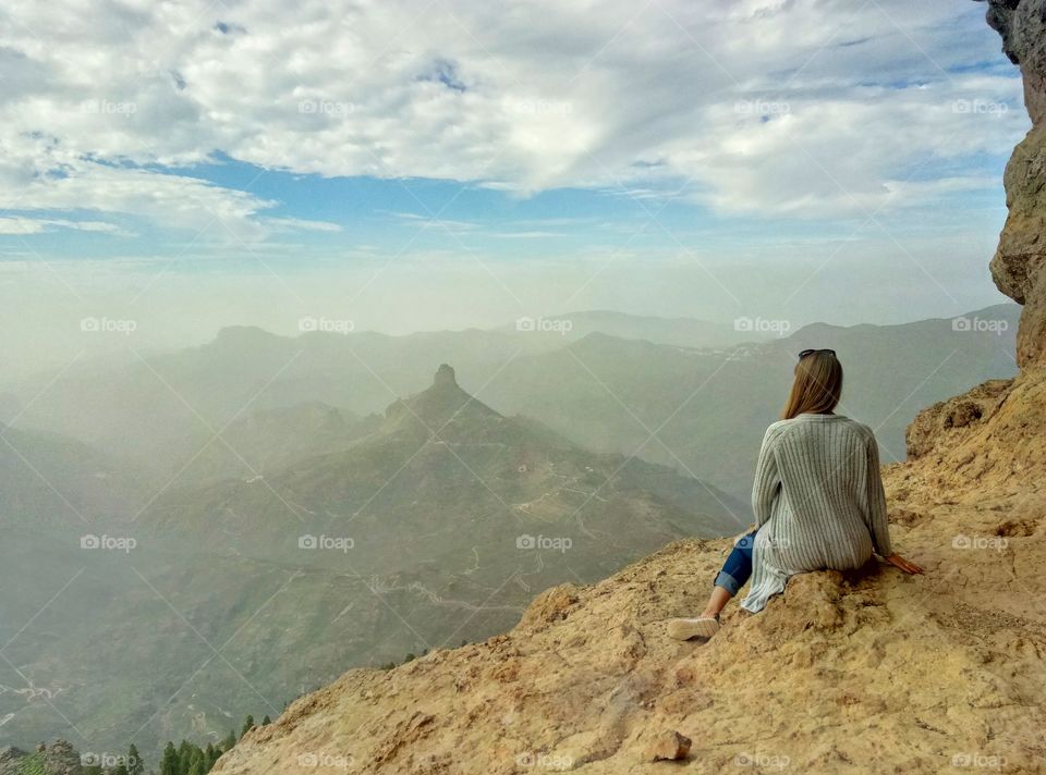 ypung woman sitting at the top of mountain on gran canaria canary island in spain