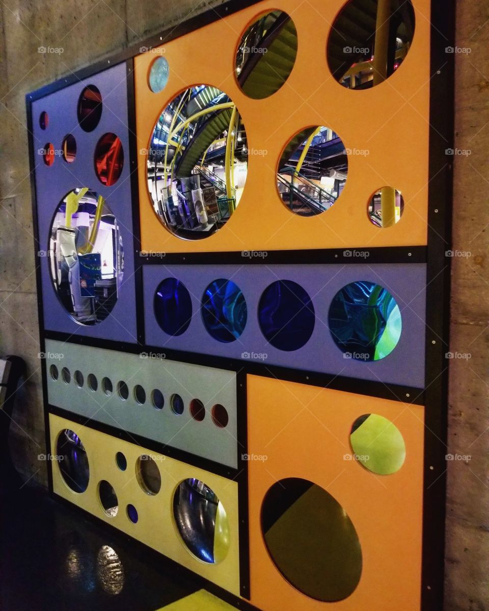 Round mirrors of various sizes on a colorful display on the wall