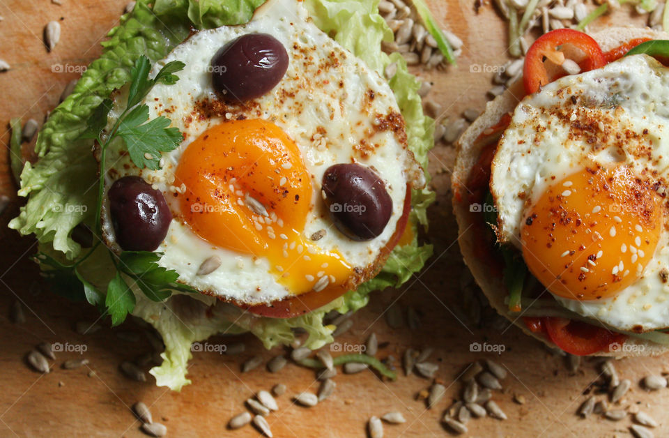 Tasty burgers with fried eggs, olives, lettuce, seeds