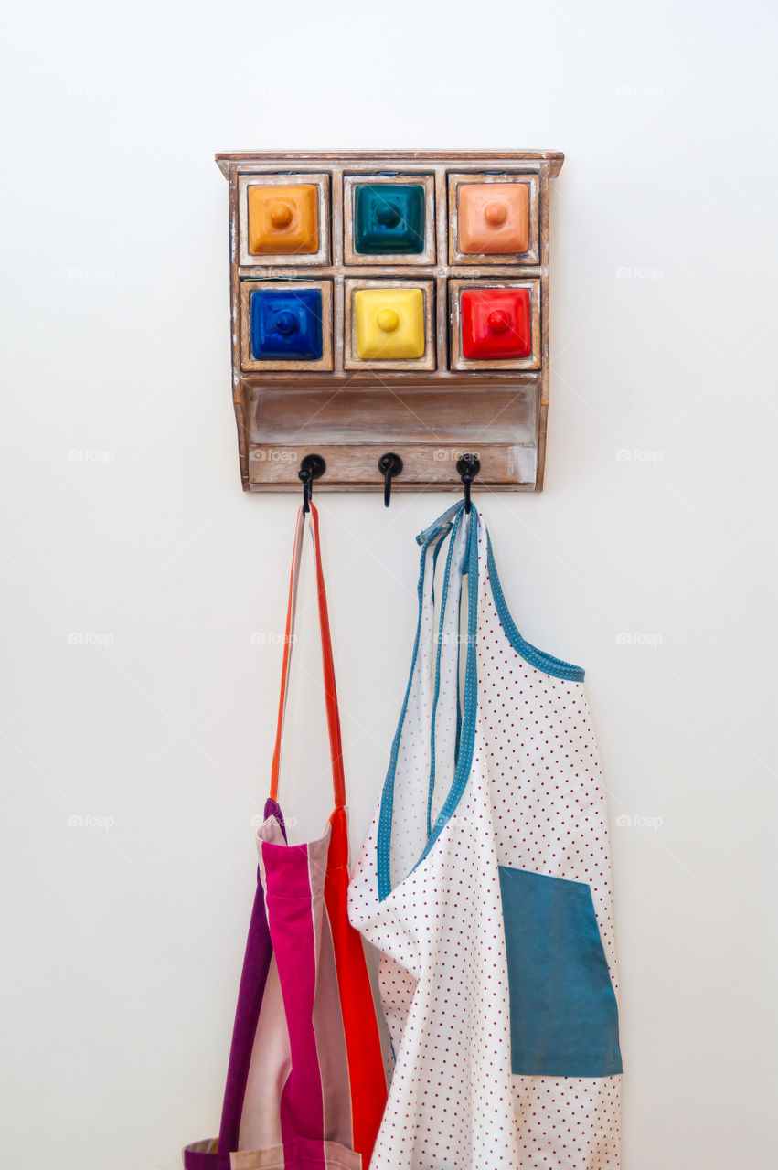 Kitchen aprons on hanger with colorful little drawers.