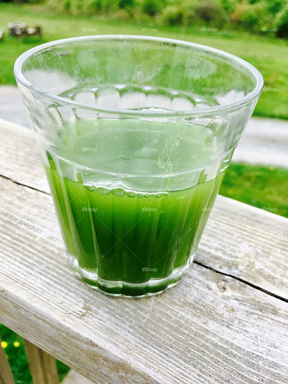 Green juice outside on wooden deck. 