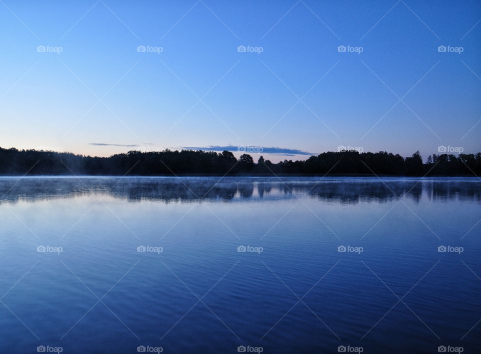 morning at the lake - silhoeutte of the forest on horizon