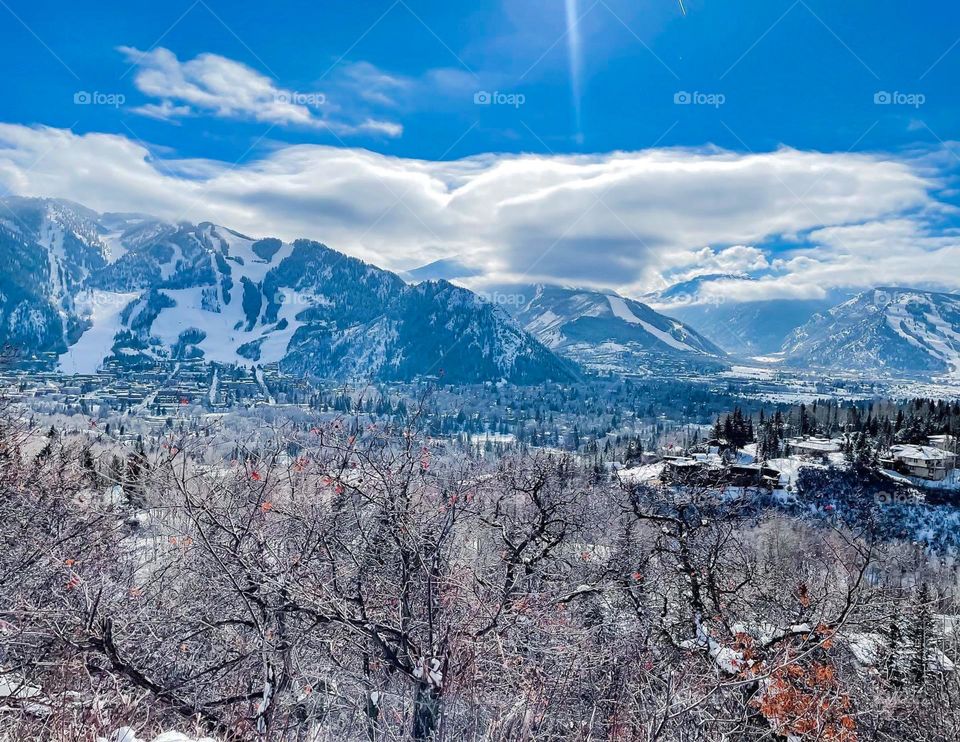 Mountains at Aspen, Colorado showing ski runs with light snow in the background and the valley below in the foreground. 