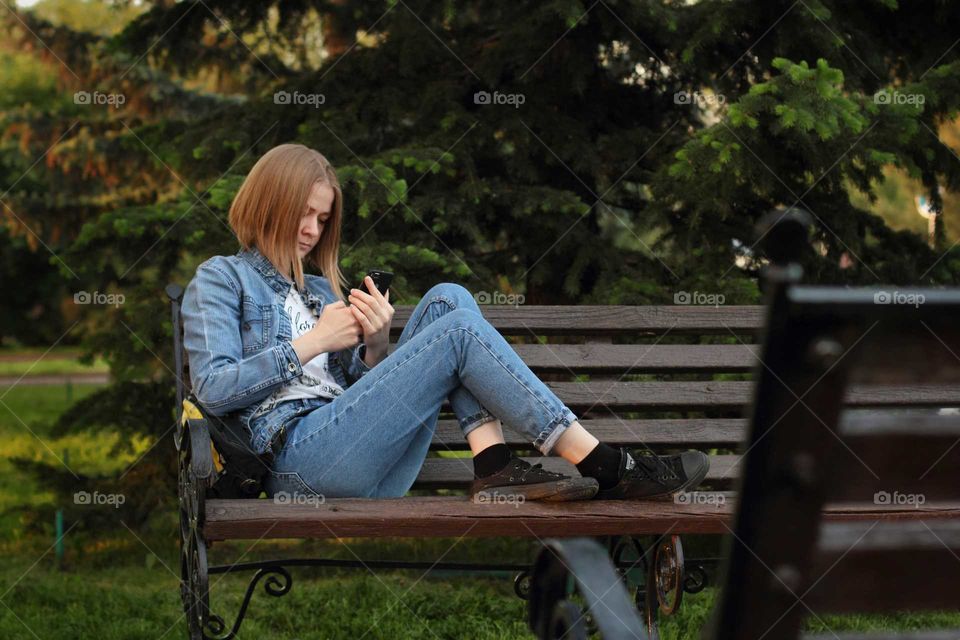 Blogging. Girl in the park parses mail in a mobile application.