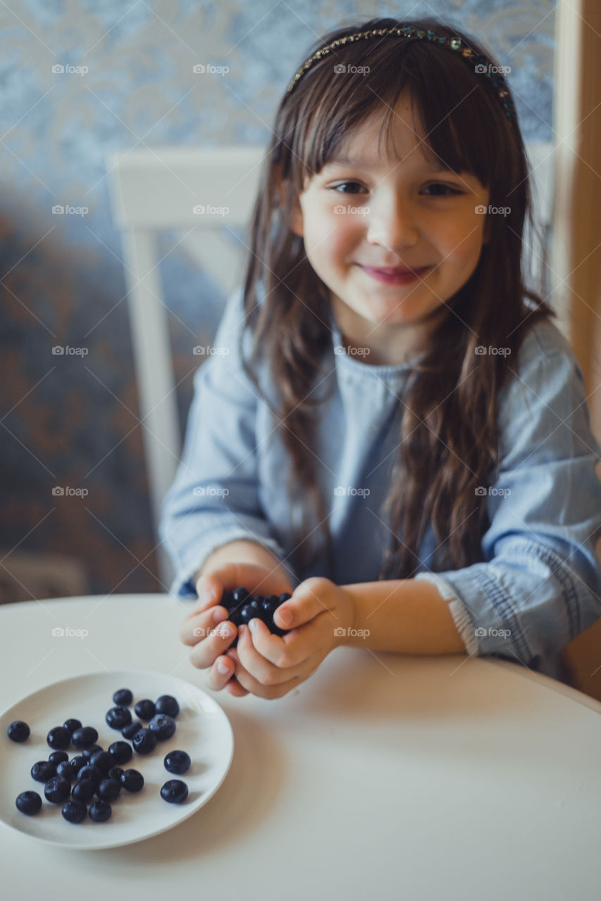 Smiling Little girl with blueberries at morning 