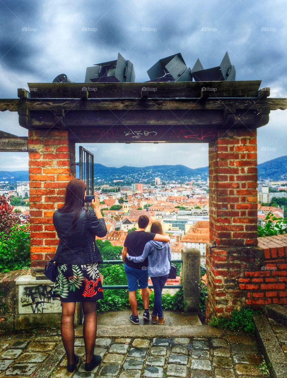 Amazing view . Capture moment of couple holding each other, enjoying the view, woman taking picture of city view