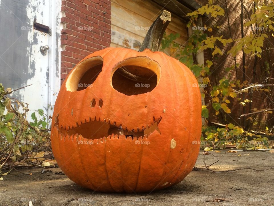 Jack'o lantern Close up.. A jack'o lantern sits out front of an abandon  warehouse.  Close up
