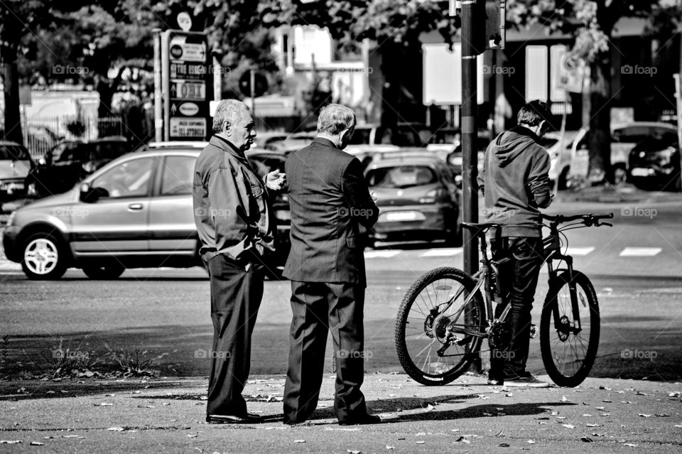 a pair of old men talk standing on the sidewalk