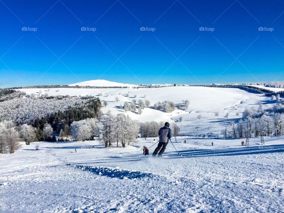 Skier going down the slope with mountains covered in snow in the background 
