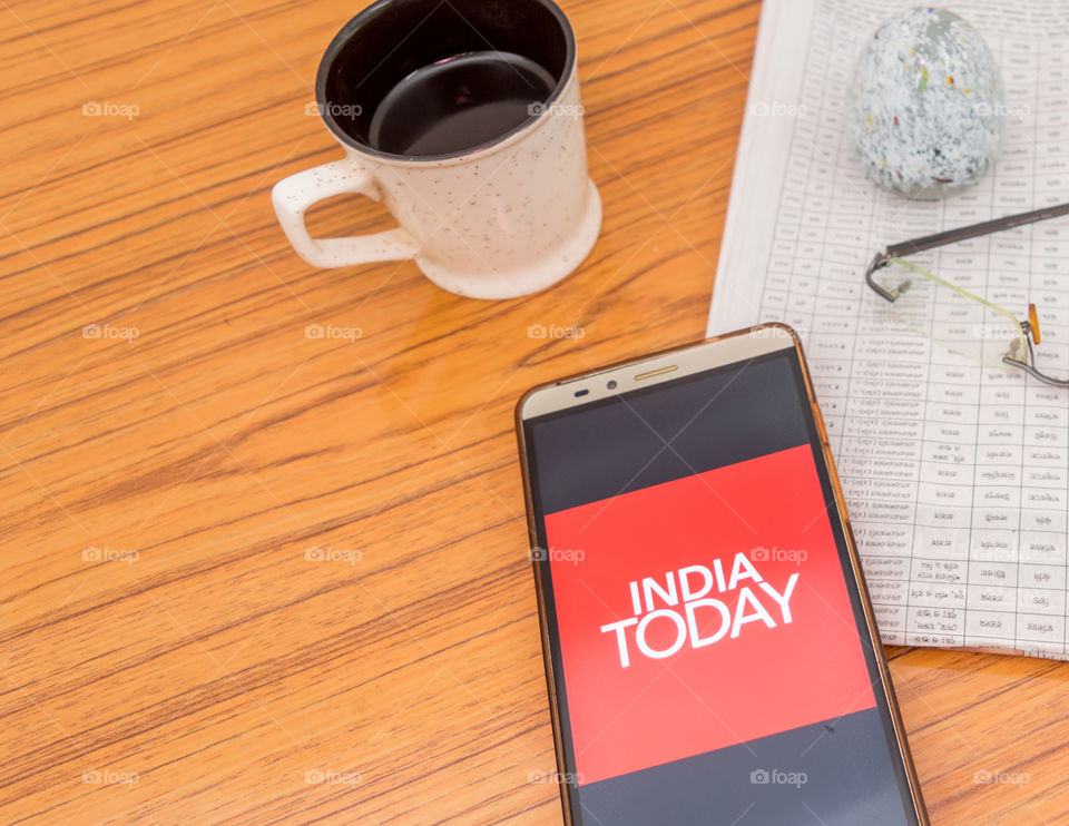 Kolkata, India, February 3, 2019: India Today news app (application) visible on mobile phone screen beautifully placed over a wooden table with newspaper and cup of coffee. A Technology Product Shoot.