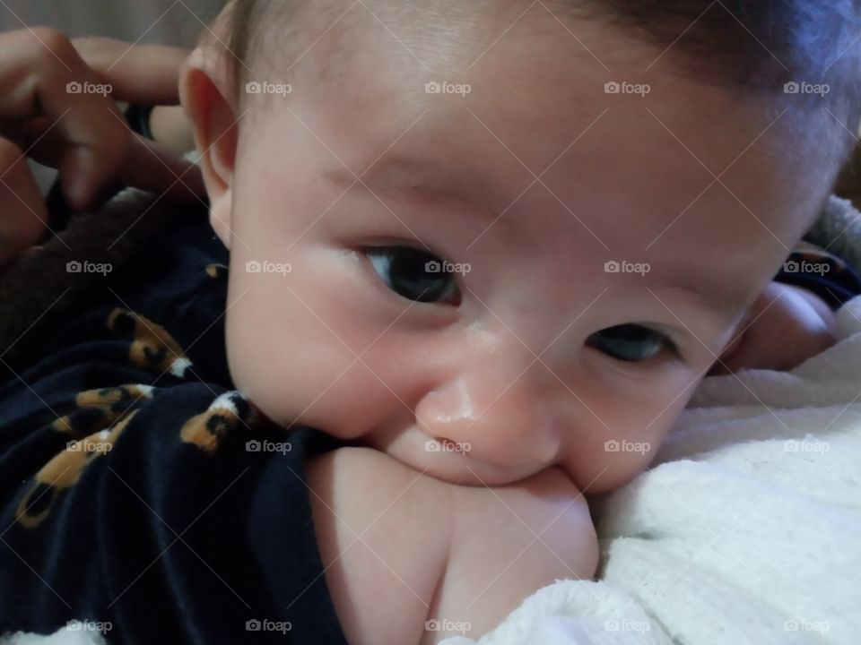 baby biting the little chubby hand
