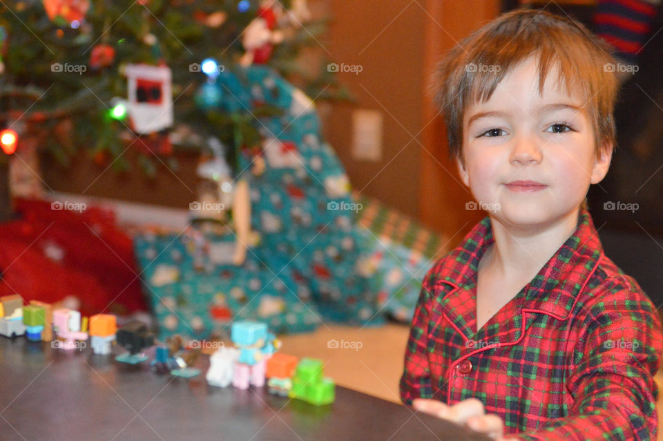 Young boy playing with Christmas toys with Christmas tree in the background