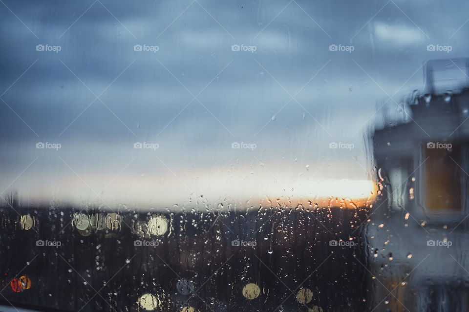 Rainy evening. Water drops on window on sunset background 