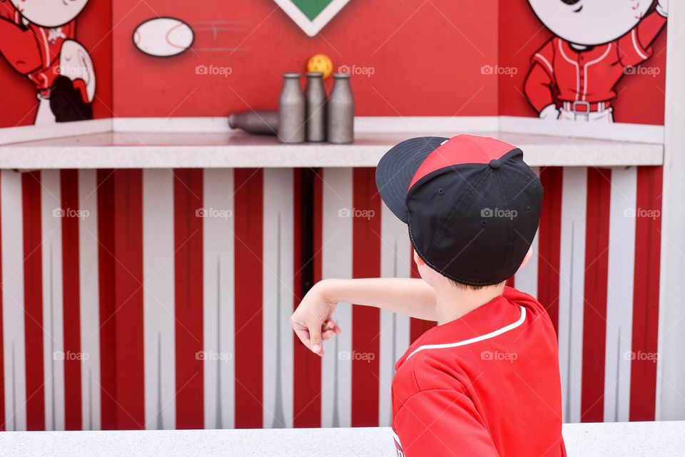 Monochromatic red image of a young boy playing a carnival ball toss game 