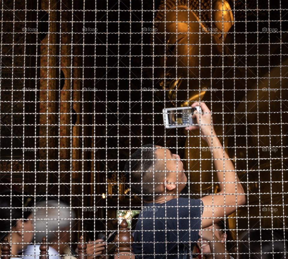 Tourist try to use smart phone to take photo the big Reclining Buddha at Wat Pho ,the Temple of  the Reclining Buddha Bangkok Thailand