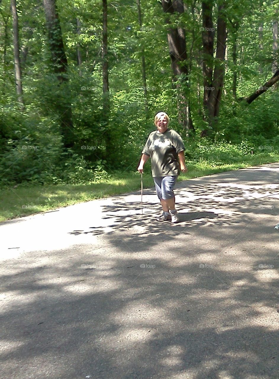 Woman walking in the shadows of the trees