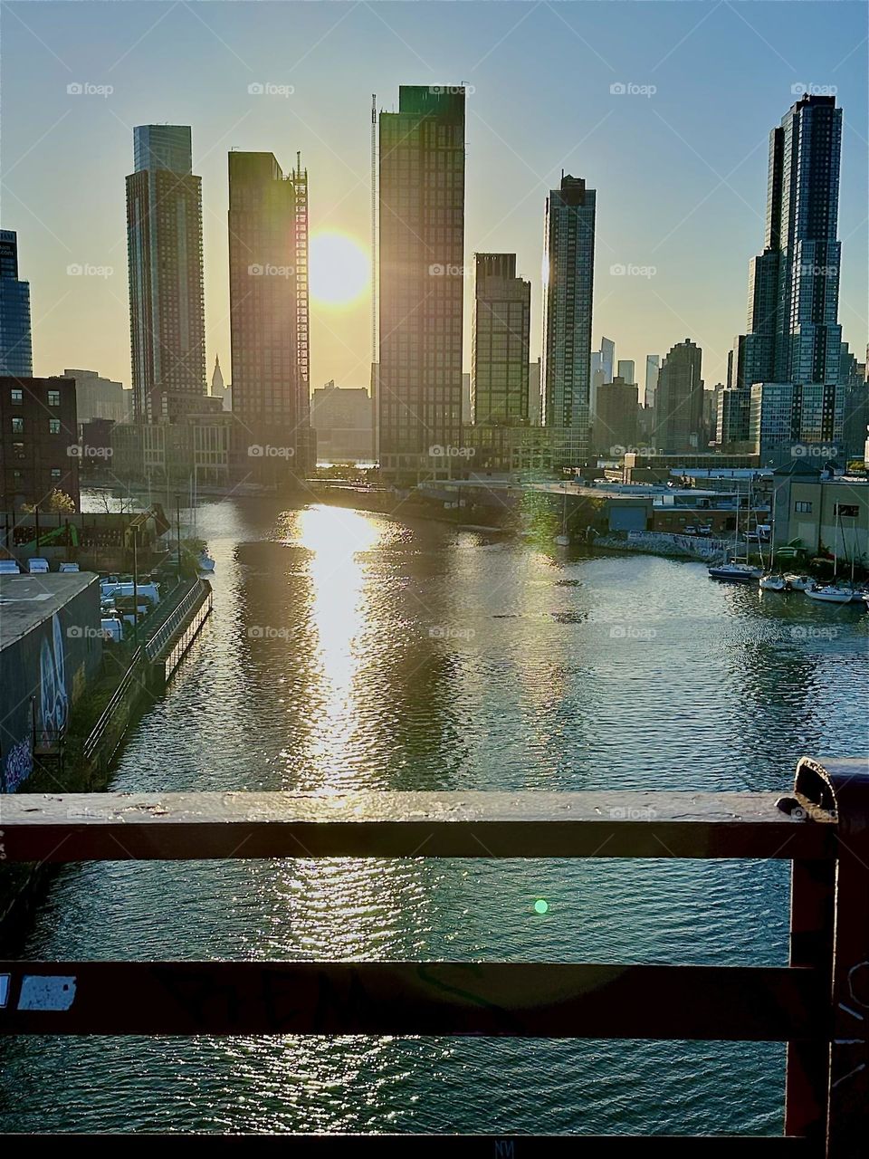 This is „Newtown Creek“ seen from the „Pulaski Bridge“ that connects „Greenpoint“, Bklyn to LIC at the golden hour of sunset before nightfall. Across the shimmering „E River“ we see „Greenpoint“, LIC and „Manhattan“. 2024. Hypnotic Productions