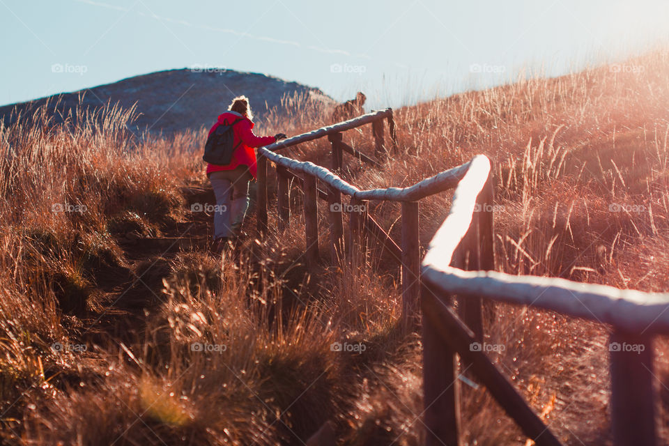 Autumn in The Bieszczady Mountains in Poland. Grass colored in many shades of brown. View of the hikers on a mountain trail from distance. Direct sunlight into the lens