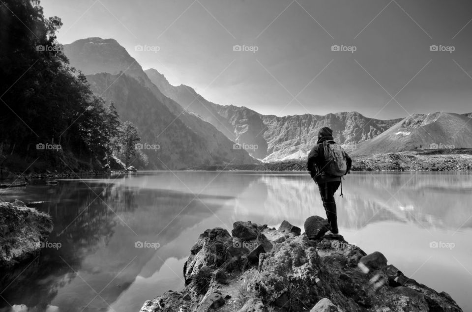black and white Beautiful nature background with unidentified hiker at Segara Anak Lake. Mount Rinjani is an active volcano in Lombok, indonesia. Soft focus due to long exposure.