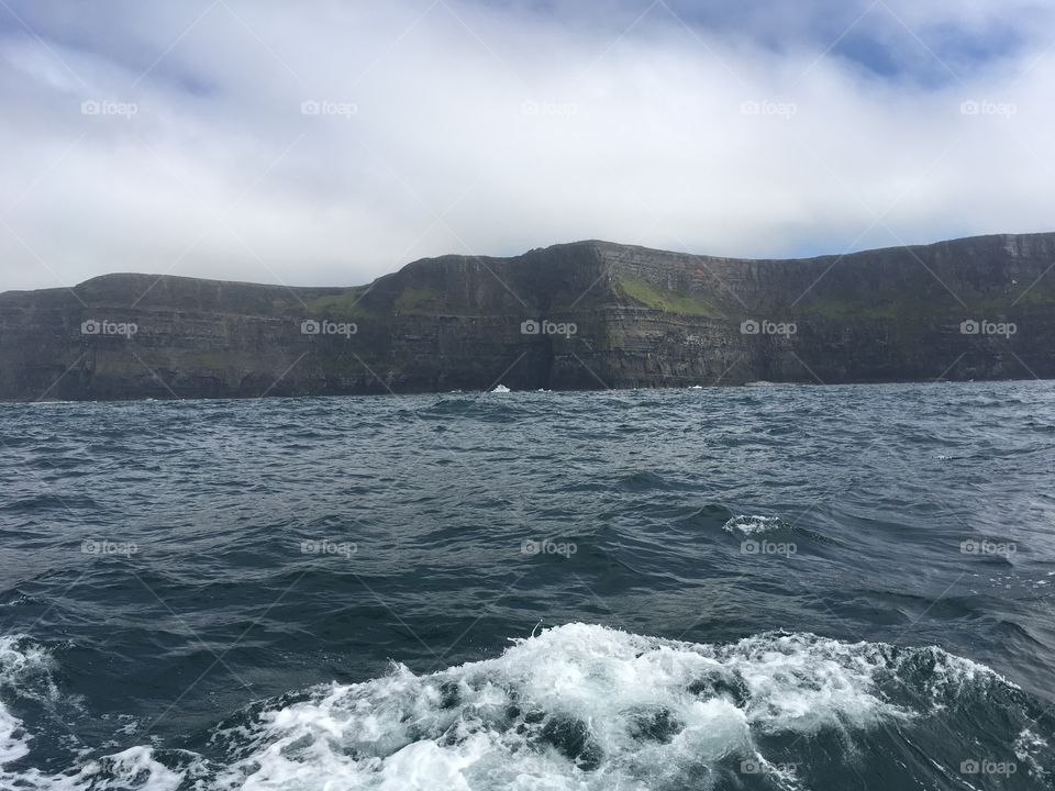 The Irish Cliffs of Moher at sea level, as cloud cover begins to thicken and a thunderstorm brews 