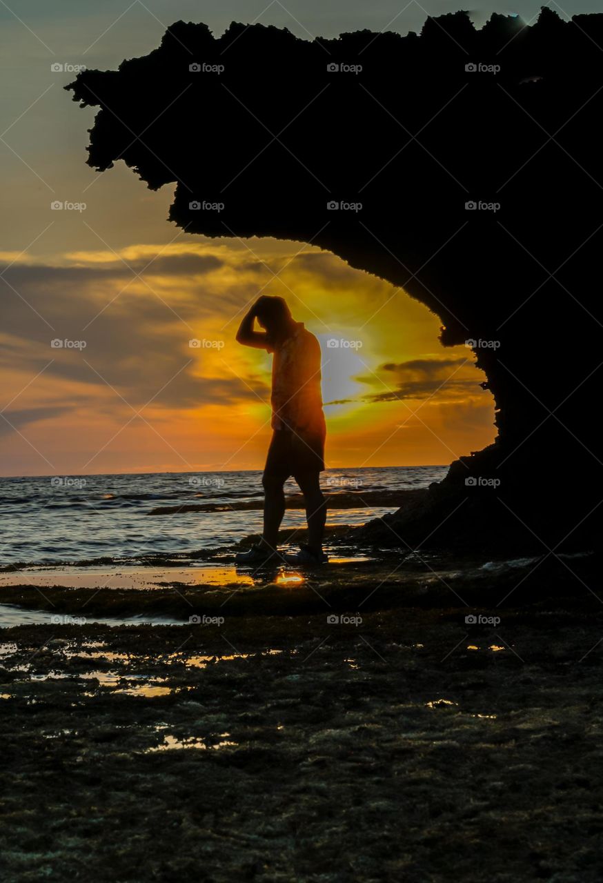 Silhouette of Alone man standing along the beach at Sunset