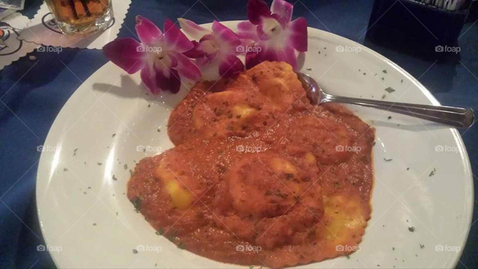 lobster ravioli. Delicious lobster ravioli with marinara sauce decorated with orchids