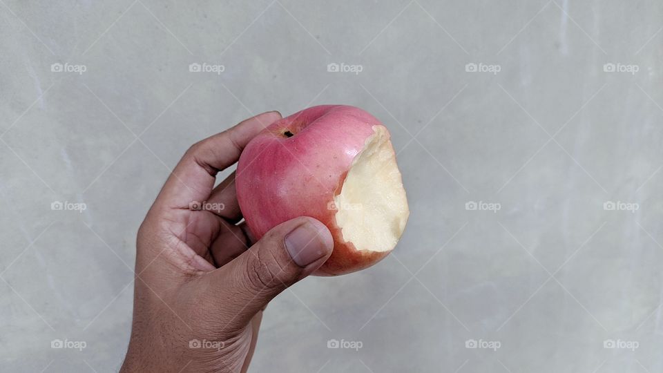Hand holding the apple that has been bitten