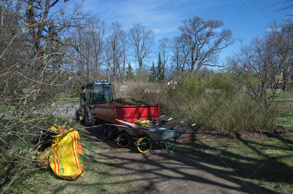 Tractor with sacks of soil and wheelbarrows in the city Botanical garden for spring garden works