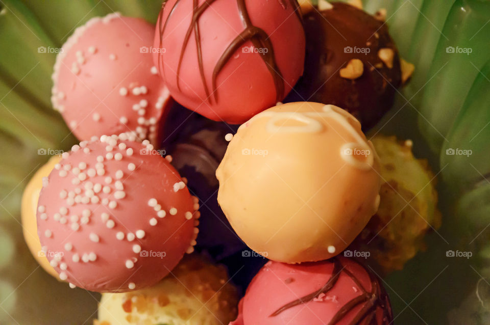 Bowl of beautiful chocolate truffles with sprinkles, nuts and chocolate ribbon in pretty spring colors 