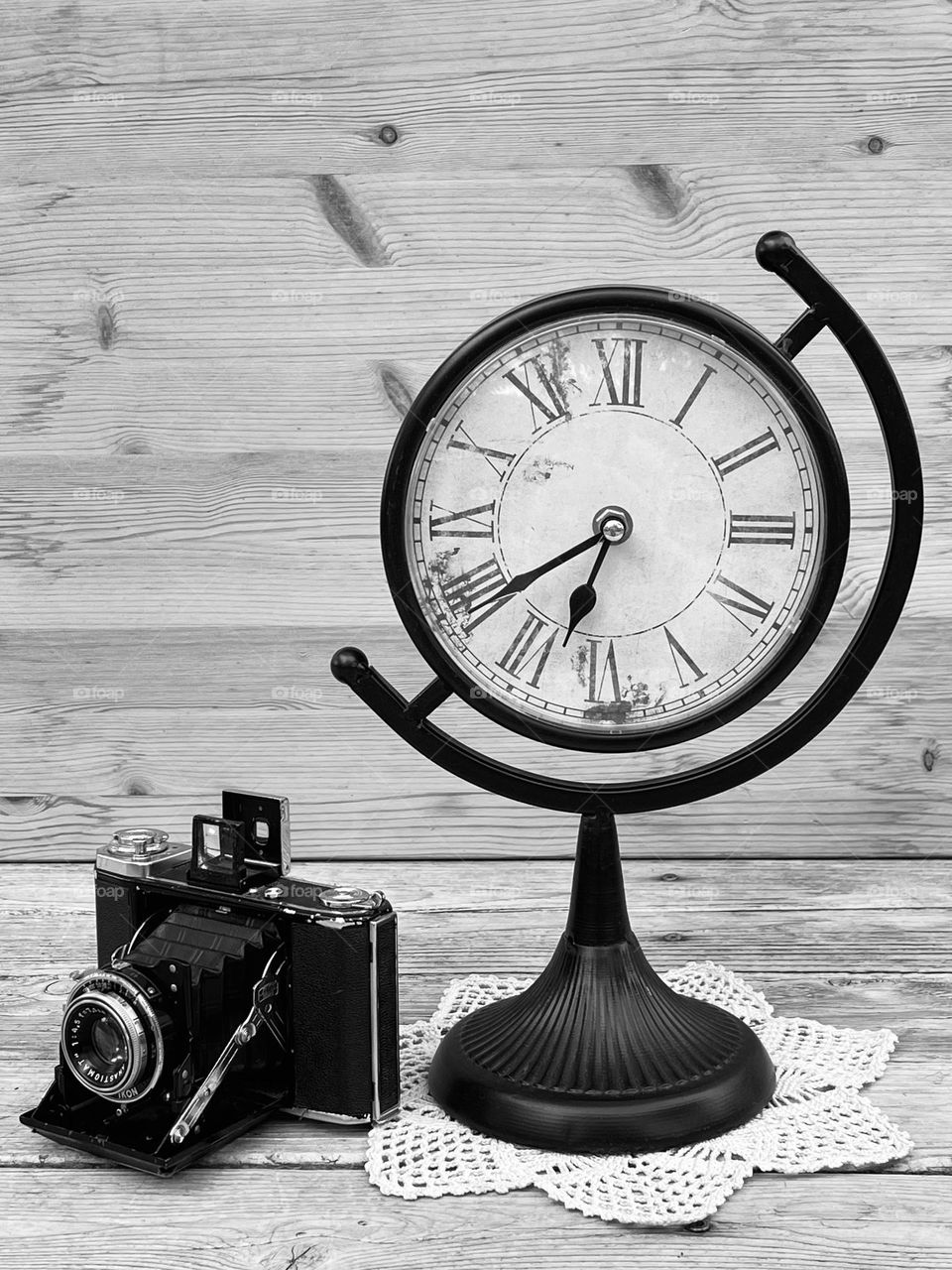 Retro camera and vintage clock on the wooden background 