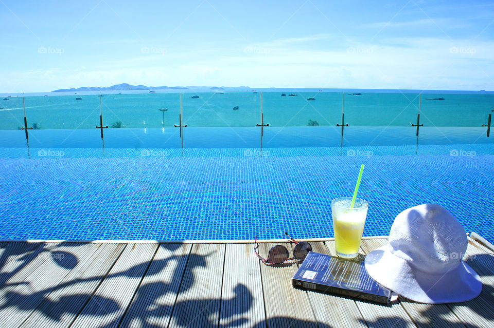 relax in summer with blue sky island view book and cocktail at swimming pool