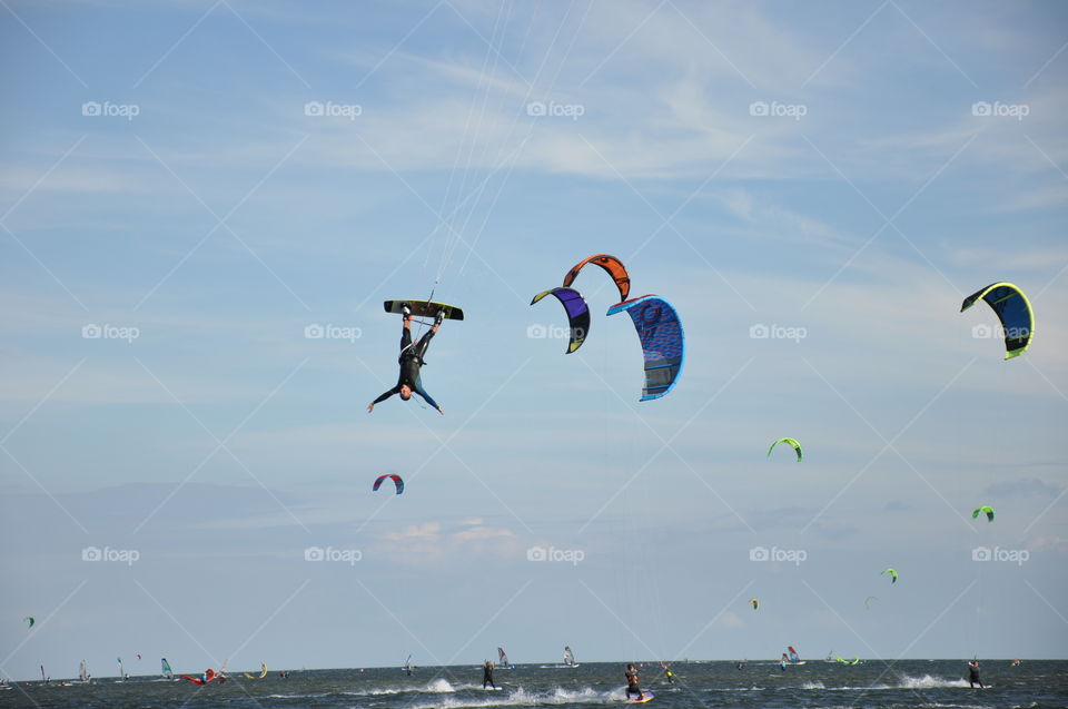 A kite surfer caught upside down while jumping over water