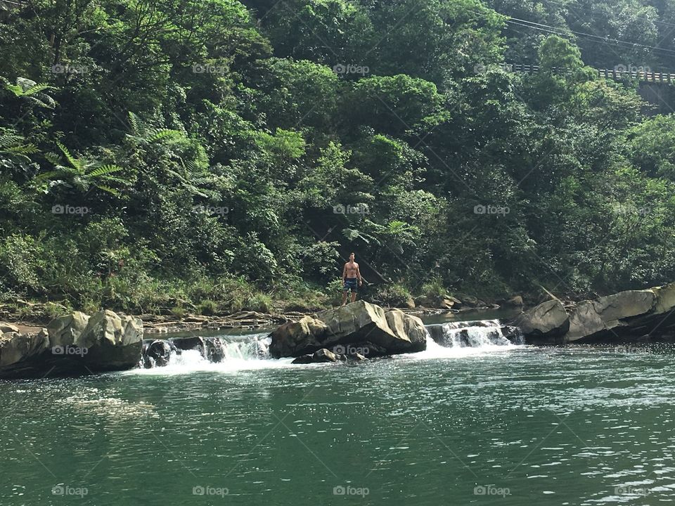 Man trying to jump on a river by a trail in Taiwan. 