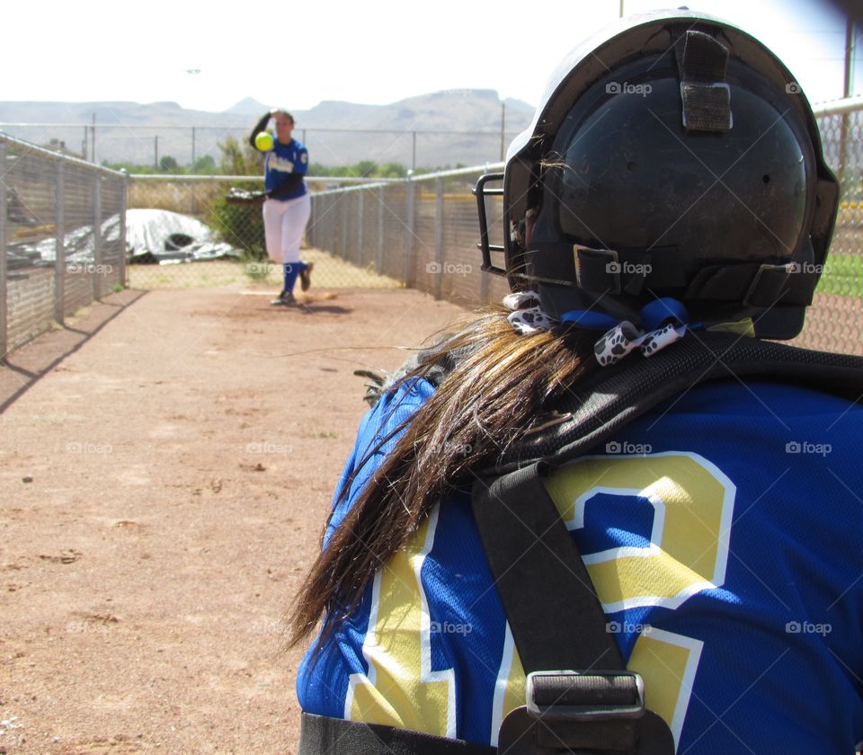 fastpitch sisters. my daughters, a pitcher and catcher warming up for varsity game