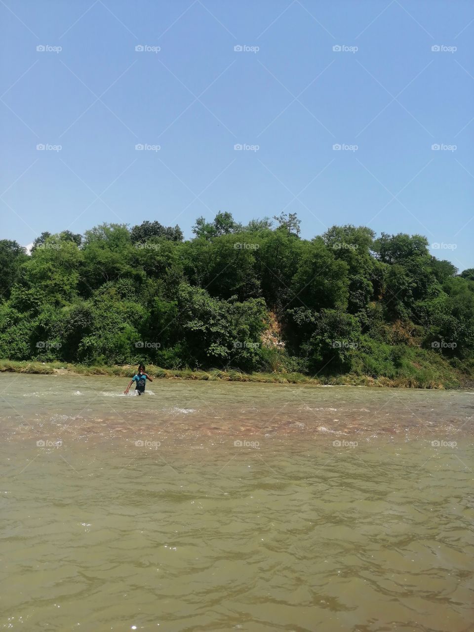 Kid crossing  the river just fun with water in summer.