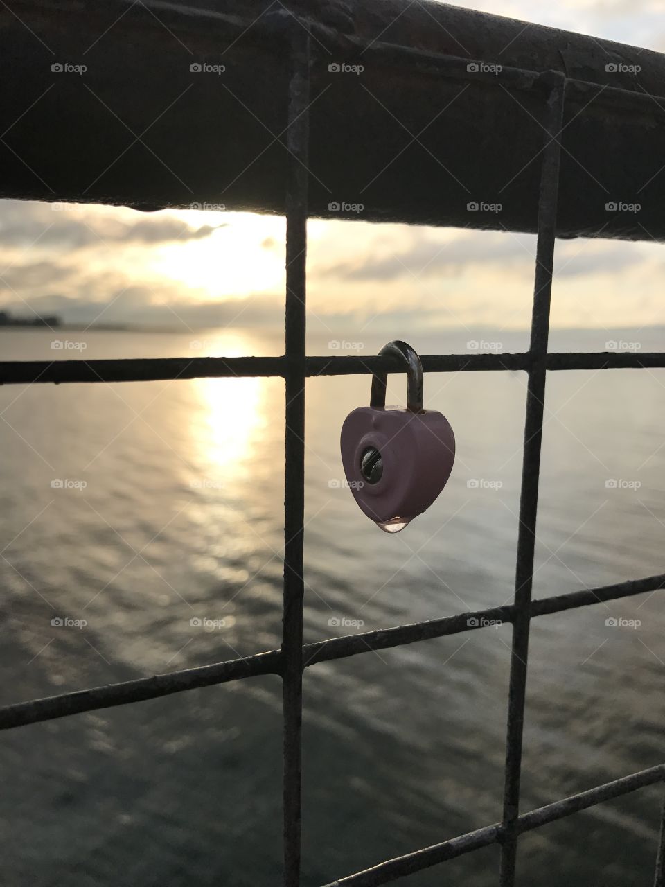 A water drop  glistens on a heart-shaped lock silhouetted by the setting sun at Newhaven Harbour in Scotland