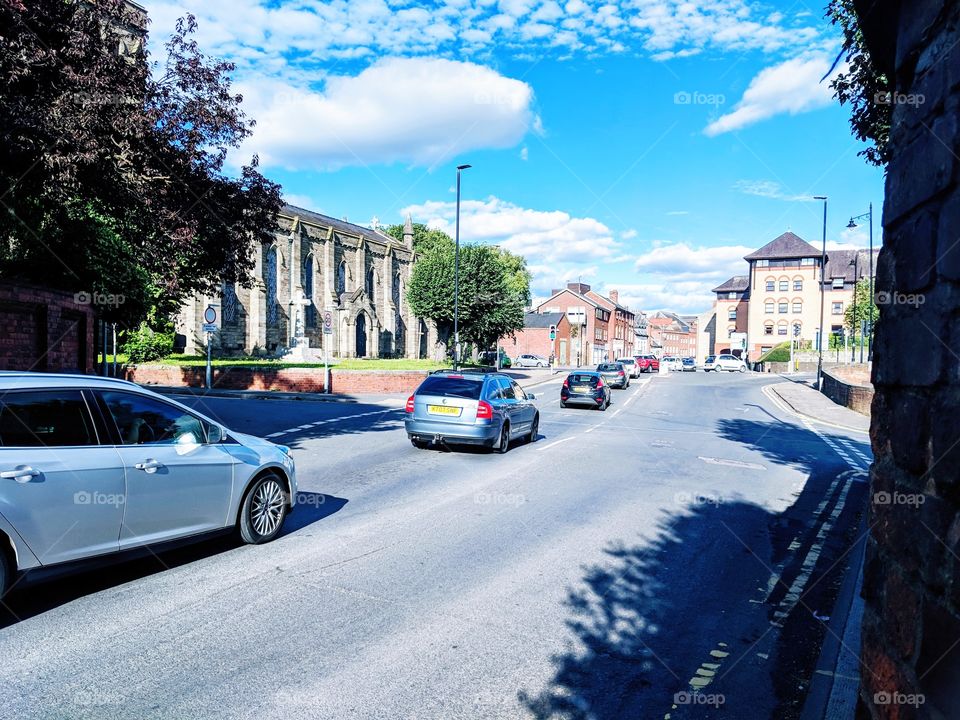 Traffic headed down a Hereford road against the backdrop of a beautiful church and idyllic skyline.