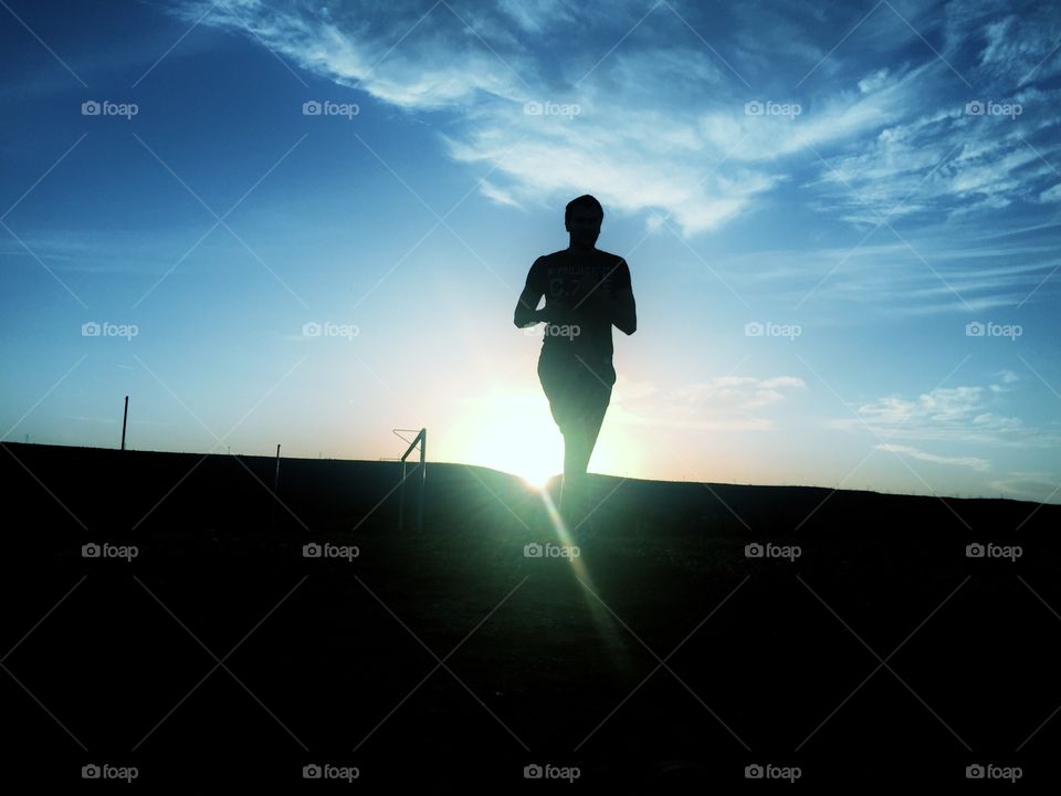 Silhouette of young man running on street