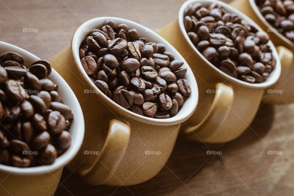 A row of 4 cups filled with coffee beans shot from above at a diagonal angle