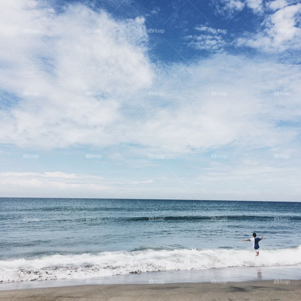 Rear view of boy playing in the waves at beach