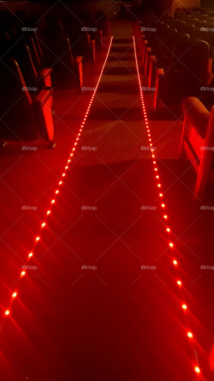 Lighted pathway down a movie theater isle.