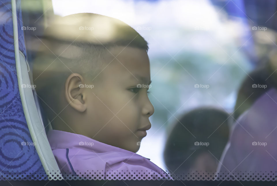 Asian boy sitting on a school bus.