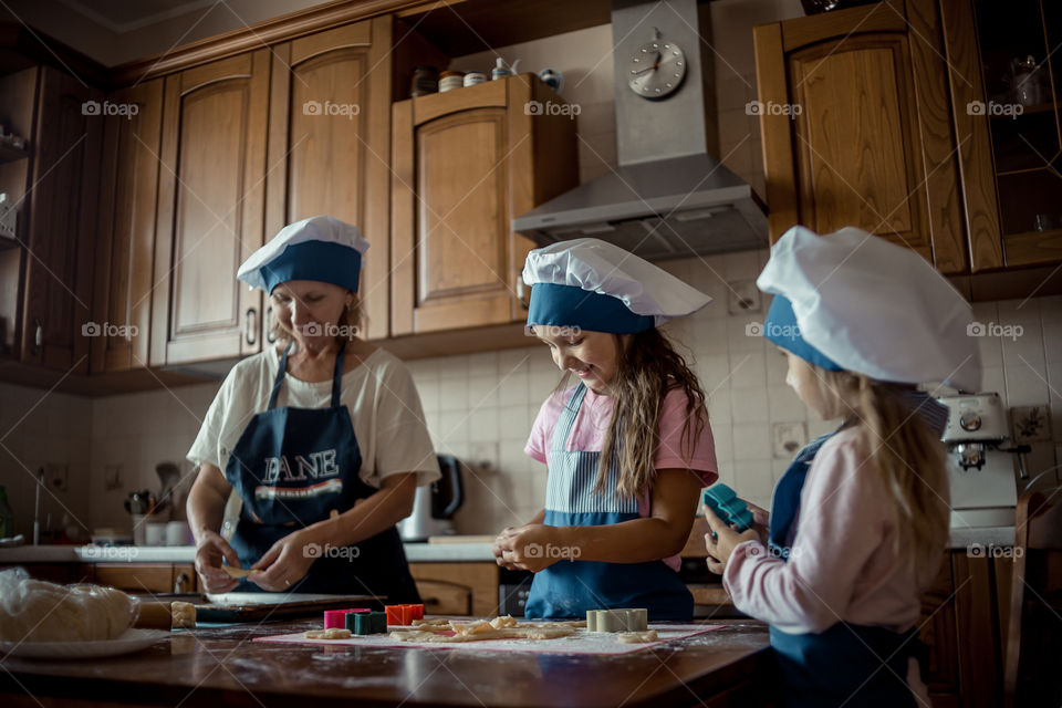 Little sisters with grandma cooking the biscuits 