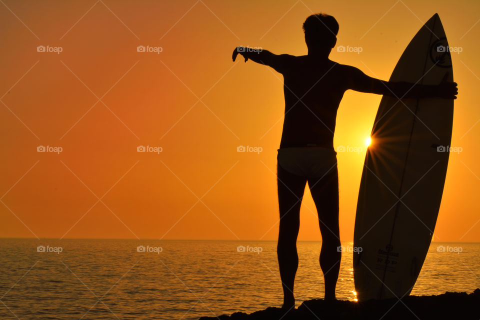 A surfer watching the waves at sunset