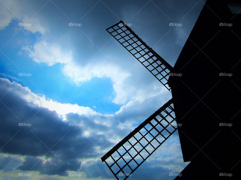 Silhouette of windmill sails with a blue sky brake in the clouds 