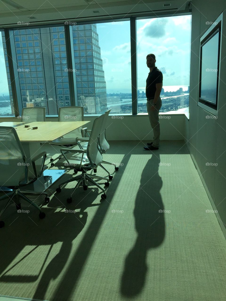 Success . Young man standing by panoramic window in office 